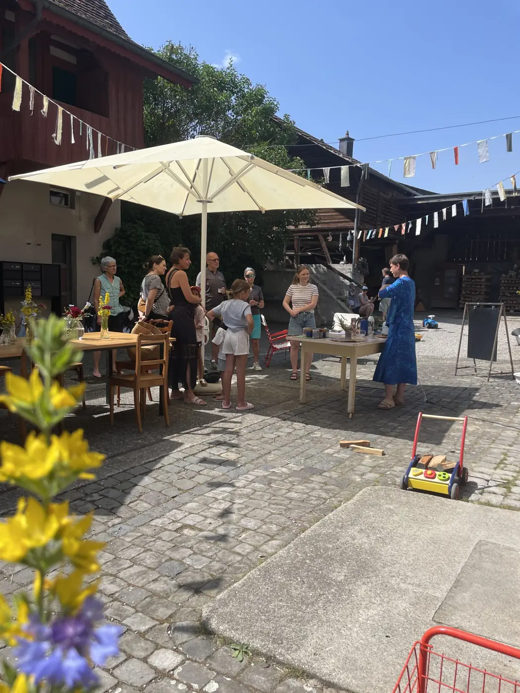 Gäste im Innenhof unter Wimpeln und Sonnenschirm